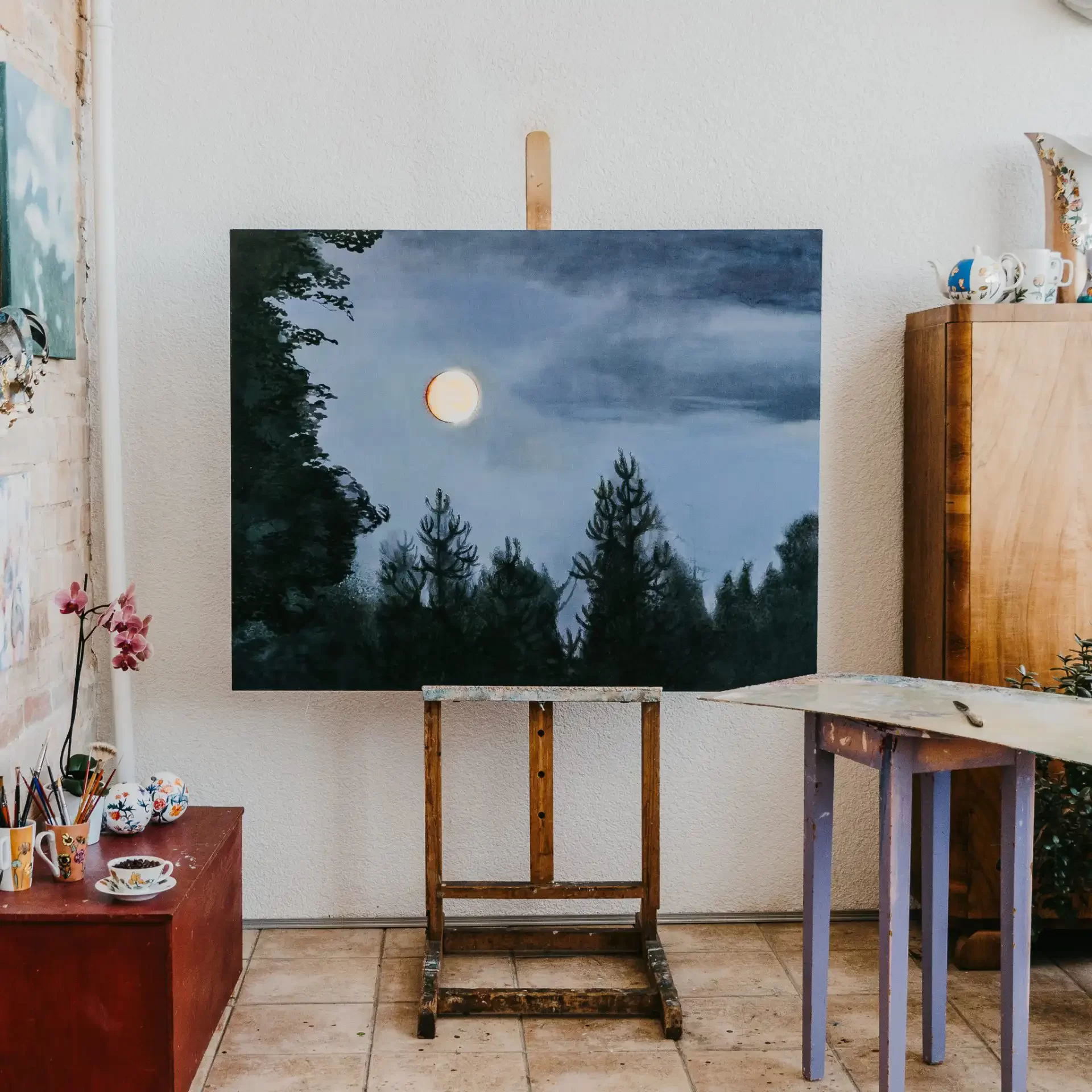 paintings of a full moon in woods in a paintersworkshop